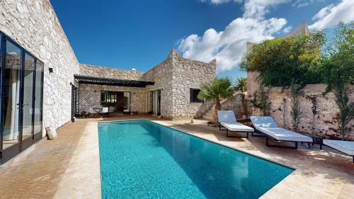 a swimming pool in front of a stone house at La Pausa du Douar in Essaouira