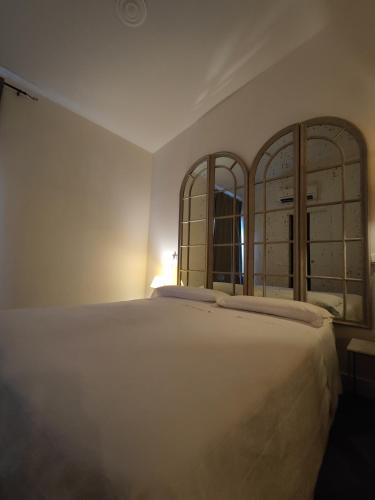 a bedroom with a large white bed with two mirrors at Botanica Loft in Montichiari Airport