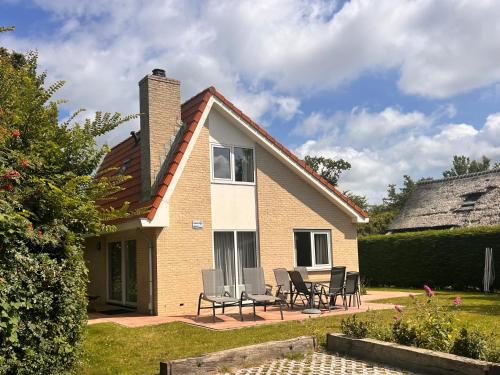 a house with chairs and a table in front of it at Vakantiehuis Hoogelandt 134 en 134a in De Koog