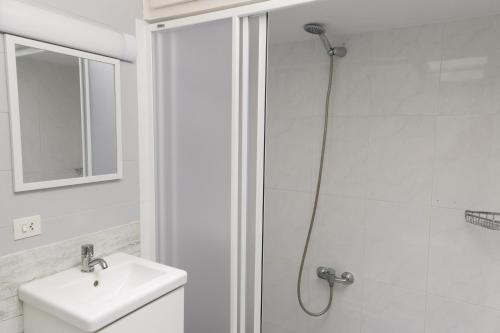 a white bathroom with a shower and a sink at Villa 10 Marias in Cala Blanca