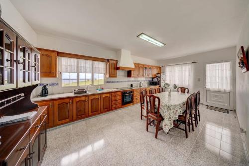 a kitchen with a table and chairs and a kitchen with wooden cabinets at Pérola Achadense Guesthouse in Achada