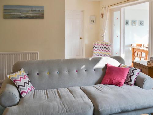 a living room with a gray couch with pillows at 61 Longstone Close in Beadnell