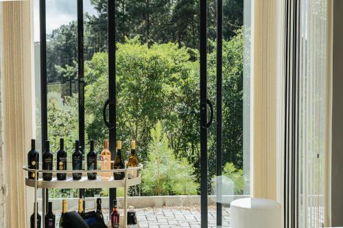 a bunch of wine bottles on a shelf in front of a window at Hotel Boutique Vinícola Araucária by Slaviero Hotéis in São José dos Pinhais