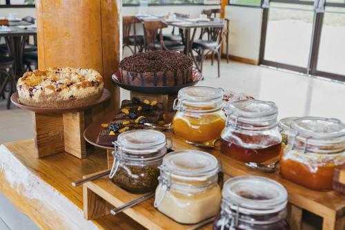 a table with several jars of honey and cakes at Hotel Boutique Vinícola Araucária by Slaviero Hotéis in São José dos Pinhais