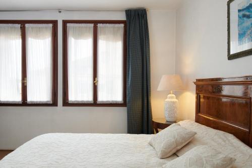 a bedroom with a bed and two windows at Palazzo Contarini Della Porta Di Ferro in Venice