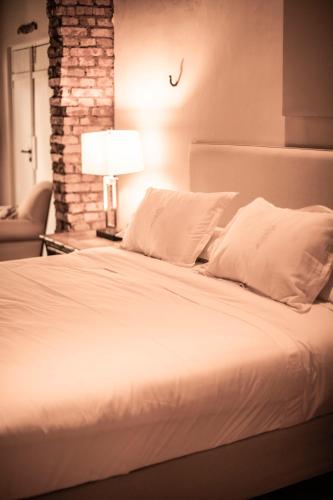 a bed with white sheets and pillows in a bedroom at Casa La Lilia - Villa María Hotel in San Bernardino