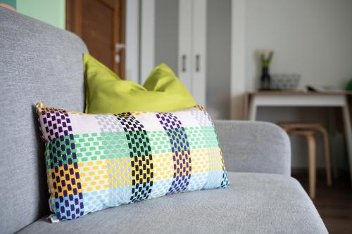 a colorful pillow sitting on a gray couch at 4 Bedroom House with Playground, BBQ & Free Parking in Rīga