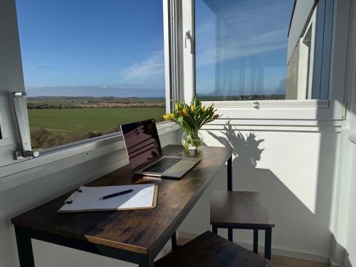 a laptop computer sitting on a wooden table in a window at Panoramablick Ostsee, Binnensee & Salzwiesen - Balkon - Stilvoll - Highspeed Glasfaser WLAN - Parkplatz - Ferienwohnung 'Freiheit' in Heiligenhafen