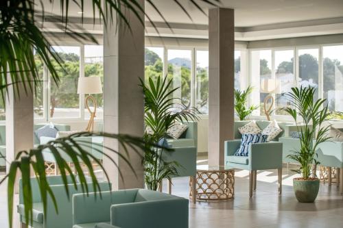 a lobby with chairs and plants and windows at MarSenses Ferrera Blanca Hotel Family in Cala d´Or
