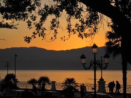 a sunset over the water with people walking at Domus Aurea in Reggio Calabria