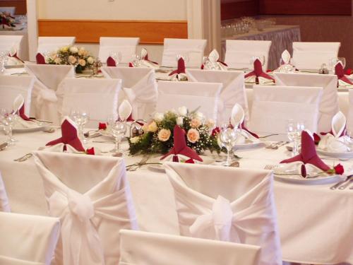 a table set up for a wedding with white tables and red napkins at Hotel Blaha Lujza in Balatonfüred