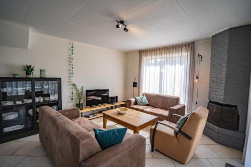 a living room with two couches and a fireplace at Vakantiehuis Hoogelandt 134 en 134a in De Koog