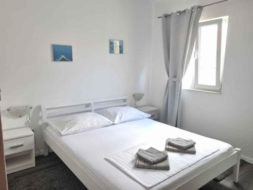 a white bedroom with a bed with two towels on it at Apartment Mimice 1 in Mimice