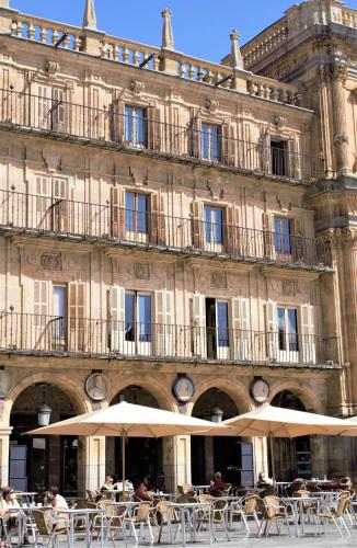 a building with tables and umbrellas in front of it at Sercotel Las Torres in Salamanca