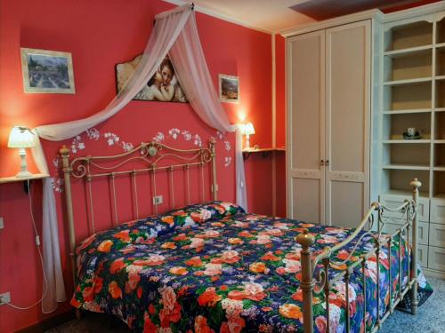 a bedroom with red walls and a bed with a floral bedspread at Villa Finetti in Gubbio