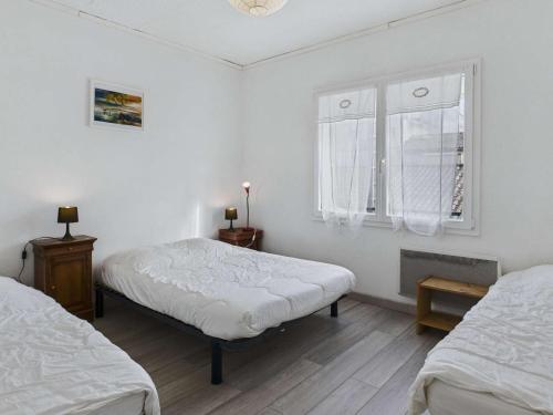 Cette chambre blanche dispose de deux lits et d'une fenêtre. dans l'établissement Appartement 3 pièces proche plage et commerces, 6 couchages, balcon – Agde - FR-1-423-198, au Grau-dʼAgde