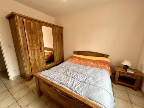 - une chambre avec un lit en bois et un miroir dans l'établissement Charmante villa 4 pers avec jardin, garage, TV et cuisine équipée - Argelès Village - FR-1-388-174, à Argelès-sur-Mer