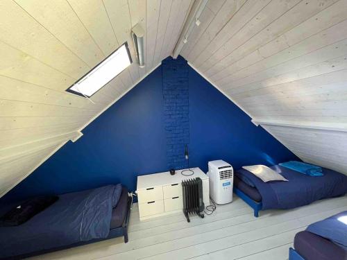 une chambre avec deux lits et un mur bleu dans l'établissement Restored loft in Trouville, à Trouville-sur-Mer