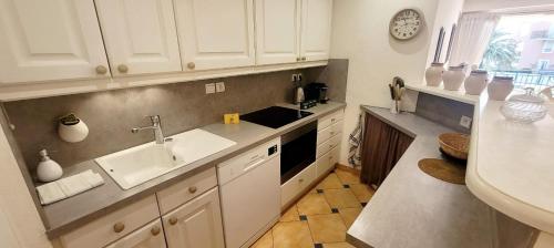 une cuisine avec des armoires blanches et un évier dans l'établissement Superb Apt Great Comfort with Balcony & Pool, à Sainte-Maxime