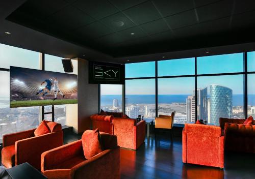 a room with orange chairs and a big screen at Swiss-Belhotel Seef Bahrain in Manama