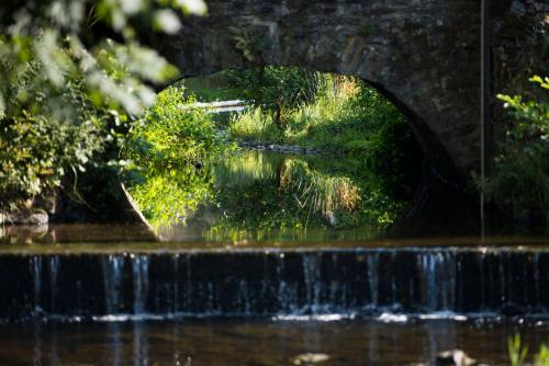 a bridge over a river with a waterfall at Les Terrasses de l'Our in Paliseul