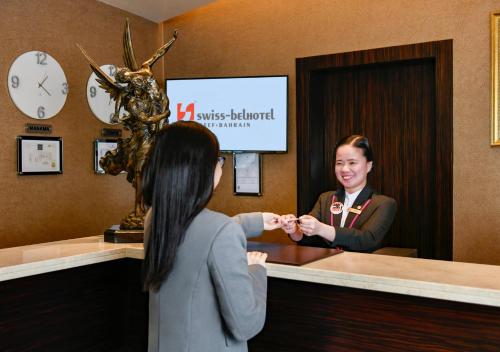 a woman is standing at a reception desk at Swiss-Belhotel Seef Bahrain in Manama