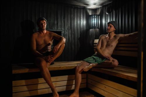 two men sitting on a bench in a sauna at Countryside Escape - Lake Rooms in Trakai