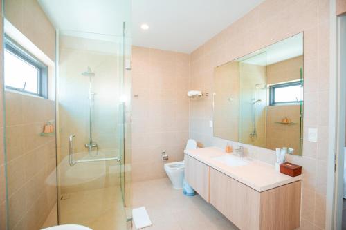 ein Badezimmer mit Toilette, Waschbecken und Dusche in der Unterkunft Beachfront 4 Bedrooms private pool villa Sanctuary Ho Tram resort in Hồ Tràm