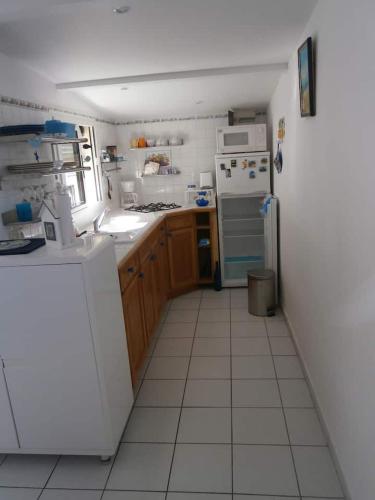 Il comprend une cuisine avec des appareils électroménagers blancs et du carrelage blanc. dans l'établissement APPART BISCA plage, à Biscarrosse
