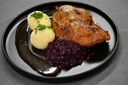a black plate of food with meat and vegetables at Das ACKER Hotel in Neuburg an der Donau