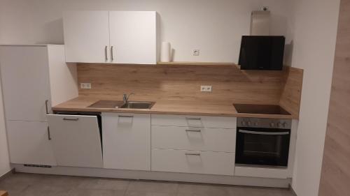 a kitchen with white cabinets and a sink at Apartment - Wohnen auf Zeit in Ursensollen