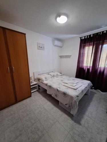 a small bedroom with a bed and a window at Apartments Dalmatin in Žuljana