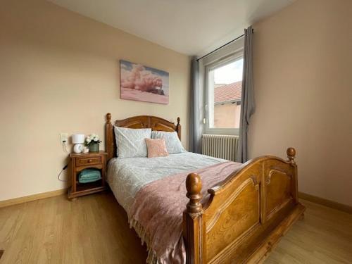 a bedroom with a wooden bed and a window at 1er etage entier, 2 Appartements, 10 Pers in Delle