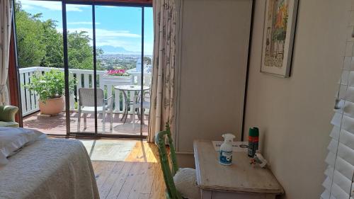 a bedroom with a bed and a view of a balcony at Martha's Place in Gordonʼs Bay