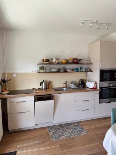 une cuisine avec des armoires blanches et un évier dans l'établissement Bright 50m apartment with magnificent lake view, à Aix-les-Bains