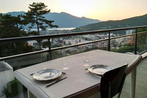 une table avec deux assiettes et des verres sur un balcon dans l'établissement Bright 50m apartment with magnificent lake view, à Aix-les-Bains
