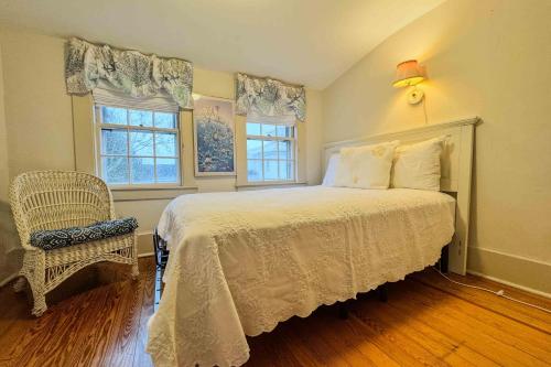 a bedroom with a bed and a chair and two windows at Captain Morse House - Luxury, Waterfront, Town, & Beaches - 5 stars in Edgartown