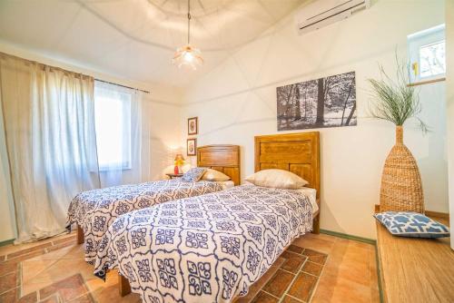 a bedroom with a bed with a blue and white comforter at Casa Peronospora by Kompas Villas in Čepljani