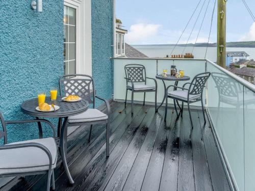 a balcony with two tables and chairs on a building at 3 Bed in New Quay 83998 in New Quay