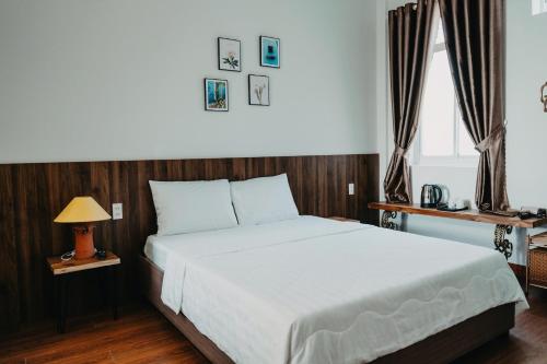 a bedroom with a large white bed and two windows at LA MER Homestay Quynhon in Quy Nhon