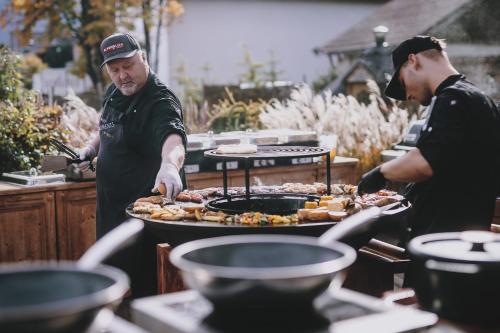 two men standing around a grill with food on it at Superior Sport und Familienresort Alpenblick in Zell am See