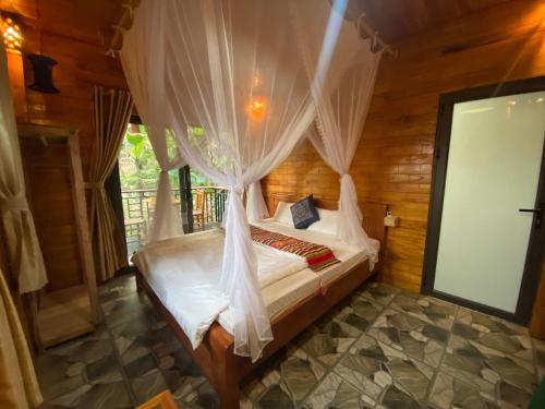 a bedroom with a bed with mosquito netting at House By The Stream in Lũng Tiềm