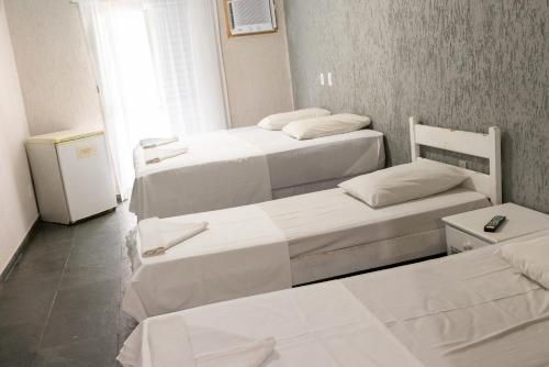 a room with two beds and a refrigerator at MOVA - Hotel Costa Azul in Ubatuba