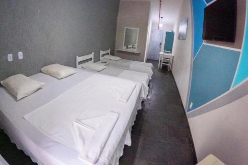 a group of three beds in a room at MOVA - Hotel Costa Azul in Ubatuba