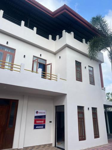 a white house with a sign in front of it at Wilson's Guest House in Nilwella