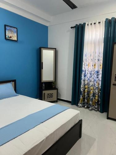 a bedroom with a bed and a mirror and blue walls at Wilson's Guest House in Nilwella