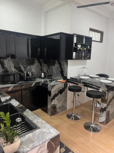 a kitchen with black cabinets and a counter with stools at Wilson's Guest House in Nilwella