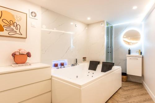 une salle de bain blanche avec un lavabo et une douche dans l'établissement Appartement d'exception avec Jacuzzi et AC - 6P, à Paris