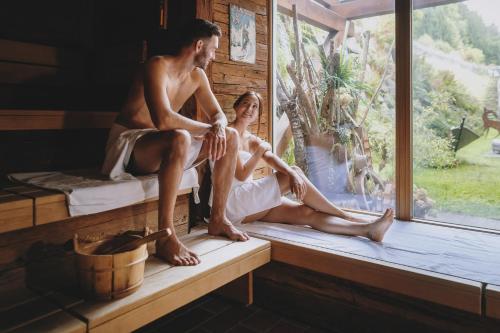 a man and a woman sitting on a window sill at Superior Sport und Familienresort Alpenblick in Zell am See