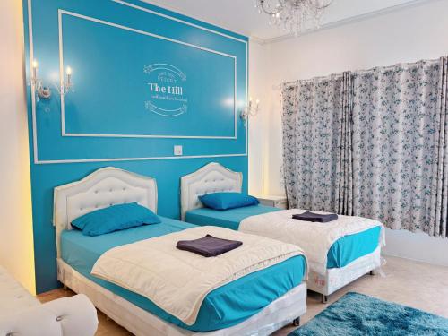 two beds in a room with blue walls at TheHill Resort เลาขวัญ in Ban Nong Masang